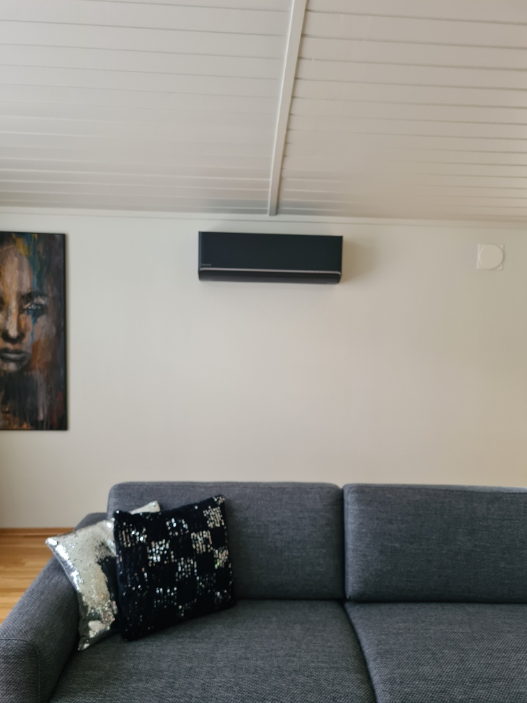 Svart varmepumpe fra Panasonic montert innendørs på husvegg